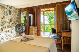 a bedroom with a bed and a desk and a fan at Casas D'Água Doce - Casa Amora in Ilhabela
