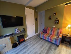 a living room with a couch and a flat screen tv at Crofters Cabin in Caernarfon