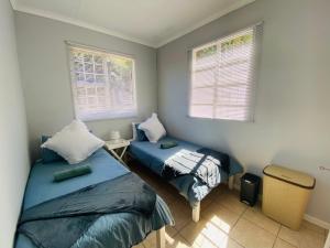 a bedroom with two beds and two windows at Beach Cresent Cottage in Port Alfred