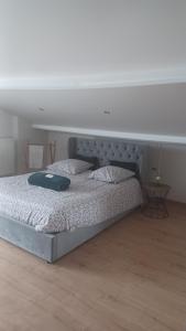 a large bed in a bedroom with a white wall at Les Deux Chambres Aucamville in Aucamville