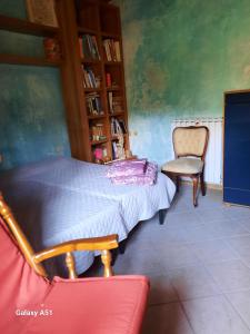 a bedroom with a bed and a chair and a book shelf at casa delle arti in Salutio