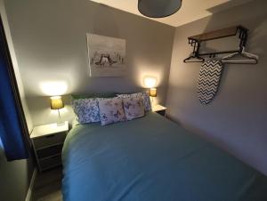 a bedroom with a bed with blue sheets and pillows at Crofters Cabin in Caernarfon +16 photos