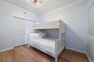 a bedroom with a bunk bed with white walls and wooden floors at Beach Club D-801 in Gulf Highlands +42 photos