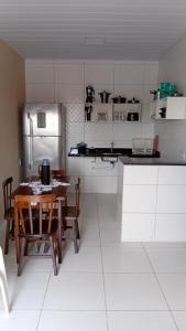 a kitchen with a table and a stainless steel refrigerator at Espaço Mãe Cecília in Paripueira +1 photo