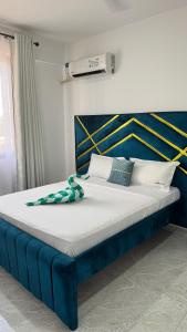 a large bed with a blue headboard and white pillows at Giannas stays 3B in Mombasa +49 photos
