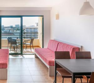 a living room with a red couch and a table at MallorcaRooms Cala Millor in Cala Millor