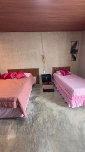 two beds in a room with pink sheets at Rancho Helena in Maceió
