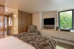 a bedroom with a bed and a tv and a chair at Memmo Príncipe Real, a Member of Design Hotels in Lisbon