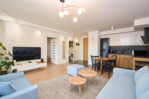 a living room with a blue couch and a kitchen at Nord-A Waterlane Island SPA in Gdańsk