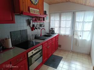 a kitchen with red cabinets and a stove top oven at KERMARIUs in Plougastel-Daoulas