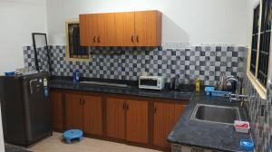 a kitchen with a sink and a black refrigerator at Comfort Zone in Chennai
