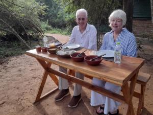 an older man and woman sitting at a wooden table at Visit Wilpattu in Pahala Maragahawewa