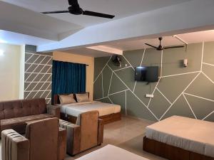 a room with two beds and a couch and a tv at Hill View Residency in Kalpetta