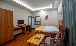 a hotel room with a bed and a table and chairs at Greenland Premium Hotel in Bhubaneshwar