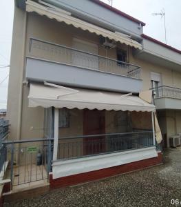 a building with a balcony with an awning at SOUROTI Pinios House in Sourotí
