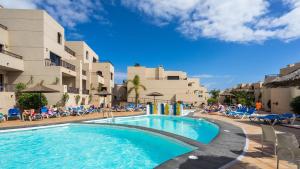 a swimming pool in front of a hotel with chairs at BLUESEA Costa Teguise Gardens in Costa Teguise +14 photos