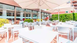 an empty restaurant with white tables and umbrellas at BLUESEA Montevista Hawai in Lloret de Mar