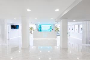 a white lobby with white columns and a reception desk at BLUESEA Interpalace in Puerto de la Cruz