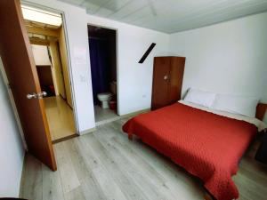 a bedroom with a red bed and a bathroom at Bohemia Hotel in Tunja
