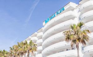 un edificio bianco con palme di fronte di BLUESEA Gran Playa a Sa Coma