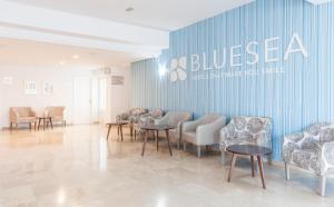 Ein Wartezimmer mit Stühlen und Tischen und einer blauen Wand in der Unterkunft BLUESEA Cala Millor in Cala Millor
