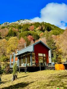 a red house with a mountain in the background at Refugio entre Montañas - Malalcahuello in Malalcahuello