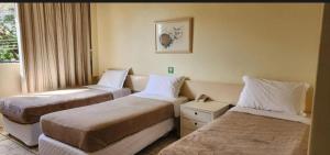 a hotel room with two beds and a window at Quarto Hotel Palhano londrina in Londrina