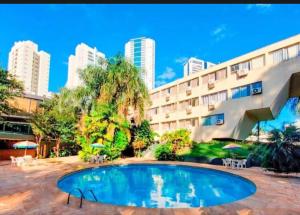a swimming pool in front of a building at Quarto Hotel Palhano londrina in Londrina