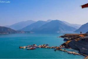 a group of boats in a body of water with mountains at Sariyal Homestay in Kandikhal
