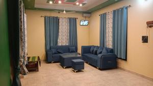 a living room with blue couches and a tv at Sariyal Homestay in Kandikhal