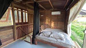 a bed in the inside of a wooden cabin at Em Cá Gỗ Farmstay in Phước Bình