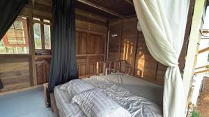 a bedroom with a bed in a room with wooden walls at Em Cá Gỗ Farmstay in Phước Bình +6 photos
