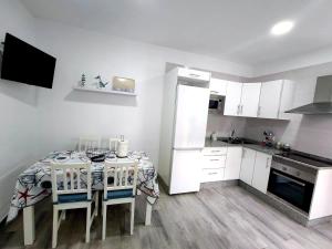 a kitchen with a table and chairs and a kitchen with white cabinets at Casa Ángela in La Restinga +5 photos