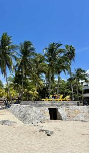 a group of yellow lounge chairs on a beach with palm trees at QUEEN ANGEL condo in Cozumel