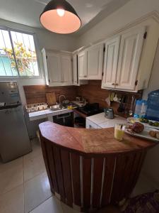 a kitchen with white cabinets and a wooden counter top at Oasis Cabarete Guesthouse in San Felipe de Puerto Plata