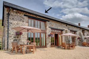 a stone building with tables and umbrellas in front of it at 1 Bed in Tiverton oc-work in Bampton