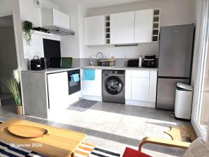 a kitchen with white cabinets and a washing machine at Spacieux appartement dans résidence avec piscine in Bormes-les-Mimosas
