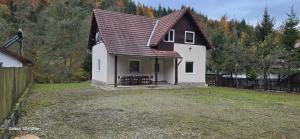 a white house with a brown roof and a yard at Vila Two in Cârțișoara