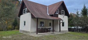 a small white house with a brown roof at Vila Two in Cârțișoara +2 photos
