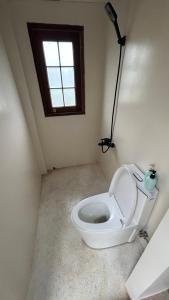 a bathroom with a toilet in a room with a window at Em Cá Gỗ Farmstay in Phước Bình