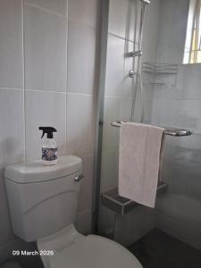 a bathroom with a toilet and a shower with a towel at Aroha Guest Apartment in Roodepoort