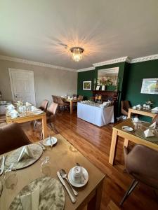 ein Esszimmer mit Tischen und Stühlen und einem Tisch mit Gläsern in der Unterkunft Killaran House in Killarney