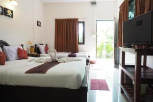 a hotel room with two beds and a flat screen tv at ภูตะวัน กาญจน์ รีสอร์ท Phutawan Kan Resort in Kanchanaburi City
