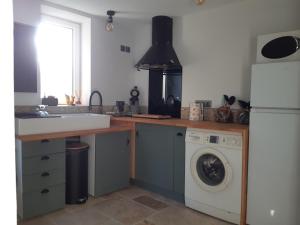 a kitchen with a sink and a washing machine at TROGLODYTE - La Grotte d'Auré in Le Puy-Notre-Dame