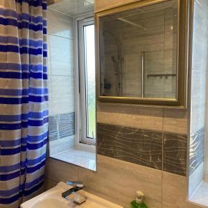 a bathroom with a sink and a mirror and a window at Robin's Accommodation in Wythenshawe