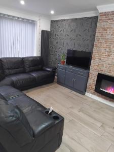 a living room with a couch and a fireplace at Robin's Accommodation in Wythenshawe