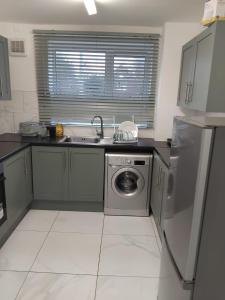 a kitchen with a sink and a washing machine at Robin's Accommodation in Wythenshawe