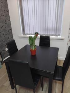 a black dining room table with a plant on it at Robin's Accommodation in Wythenshawe +18 photos