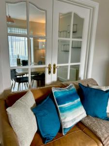 a couch with blue pillows sitting in a living room at North Coast Nook in Portrush
