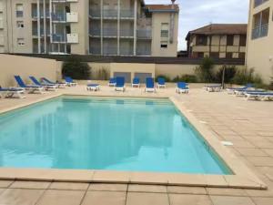 a large swimming pool with blue chairs and chairs at Studio proche océan dans résidence 3 étoiles avec piscine et parking privé in Mimizan-Plage